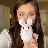 Person holding a knitted white bunny with pink ears.