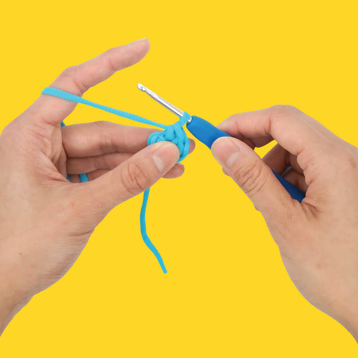 Hands using a crochet hook with blue yarn on yellow background.