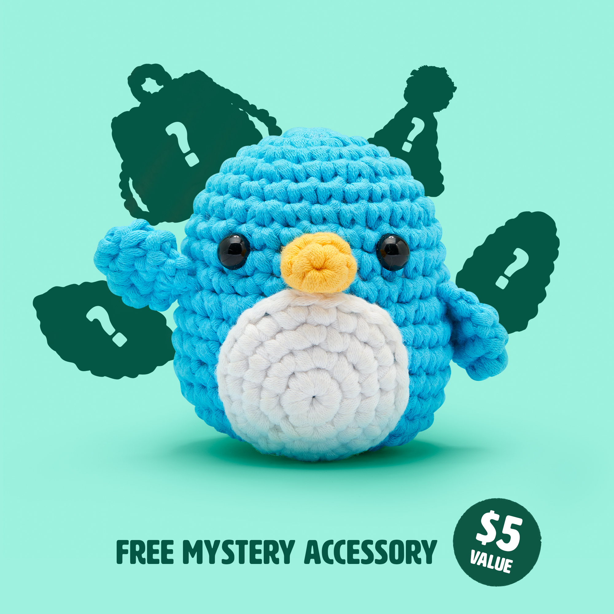 Crocheted blue penguin toy with question marks and text about a free mystery accessory.