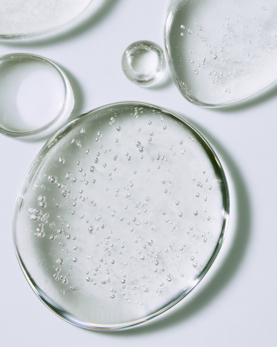 Several circular drops of clear liquid with bubbles sit on a plain white surface.