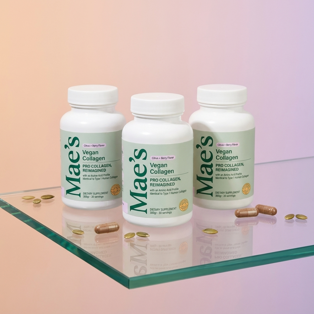 Three bottles of Mae's Vegan Collagen on a glass surface with scattered capsules.