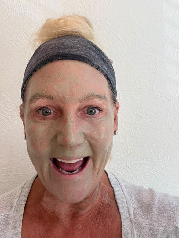 Person with facial mask and headband smiling at camera.