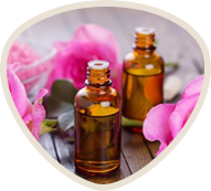 Two amber bottles with pink rose petals on a wooden surface.