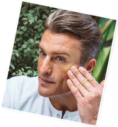 Man applying skincare product to his face, outdoors.