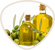 Two bottles of olive oil with fresh olives around them.