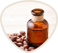 Brown glass bottle surrounded by nuts on a light surface.