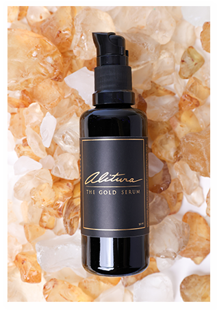 Black bottle of gold serum on amber stones background.