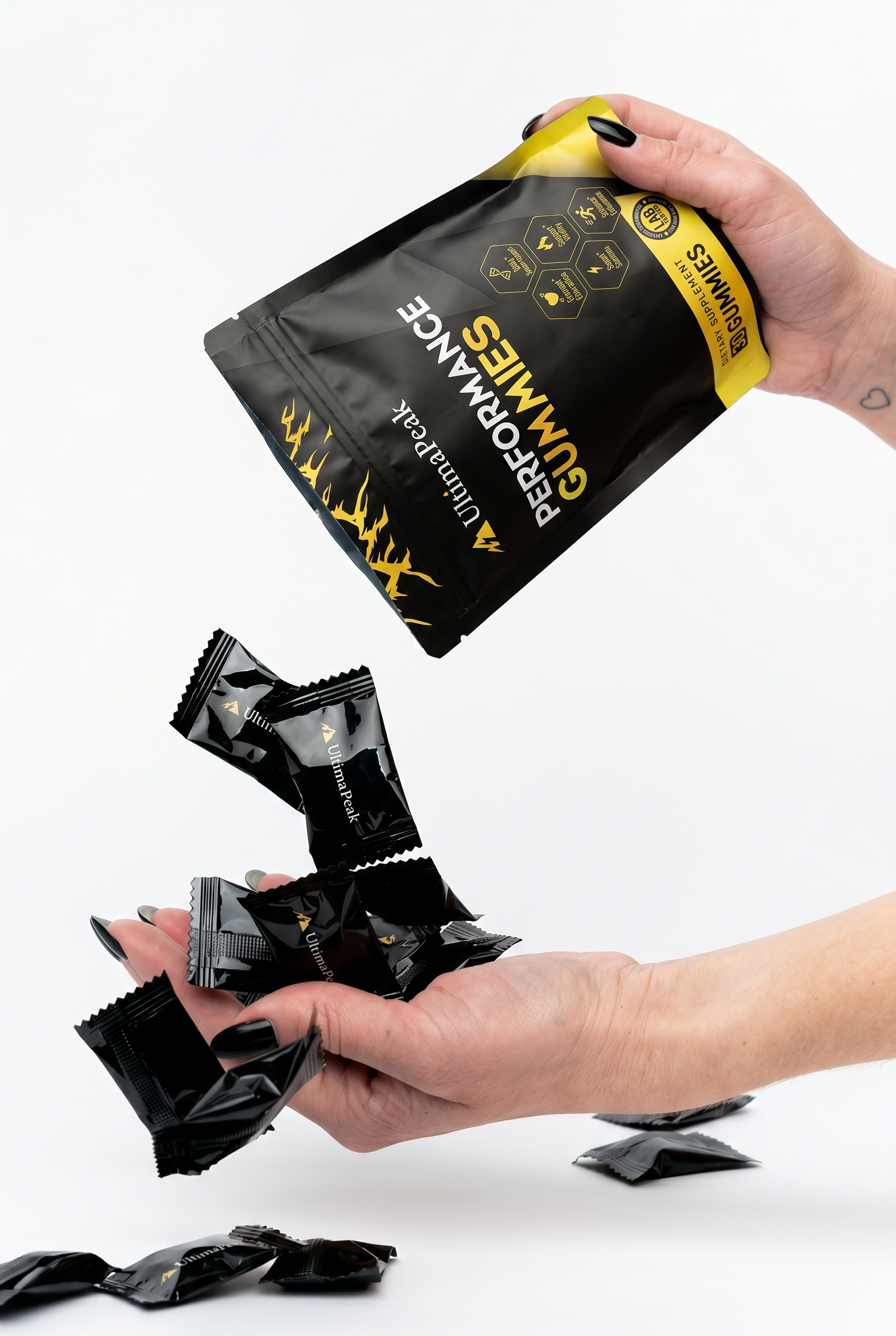 A person pours individually wrapped UltimaPeak performance gummies from a pouch into their hand against a white background.