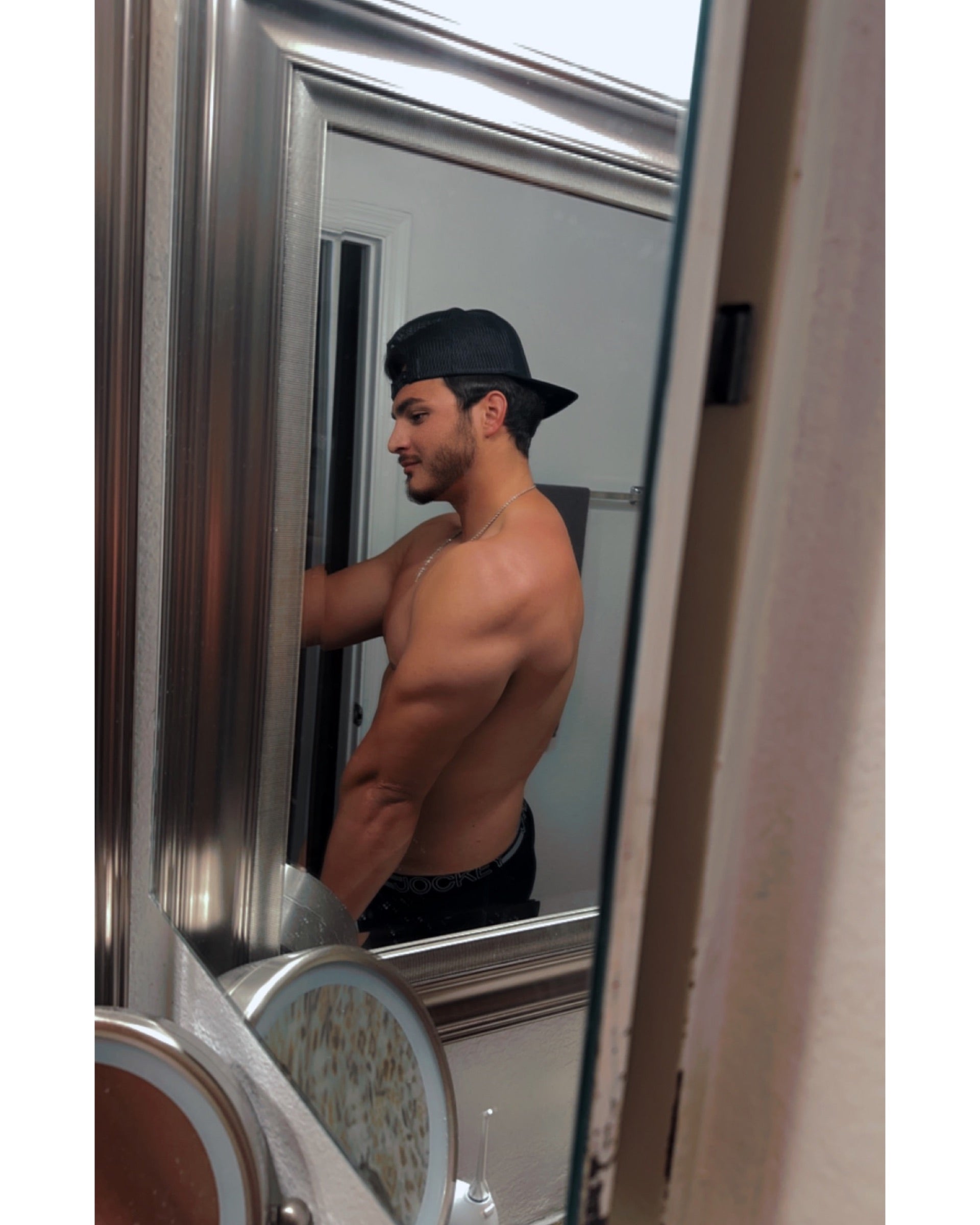 Man in a cap looking at his reflection in a mirror.
