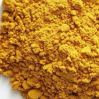 Close-up of a pile of bright yellow powder on a white surface.
