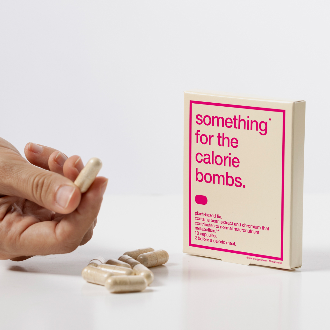 Hand holding a capsule near a box labeled 'something for the calorie bombs.'