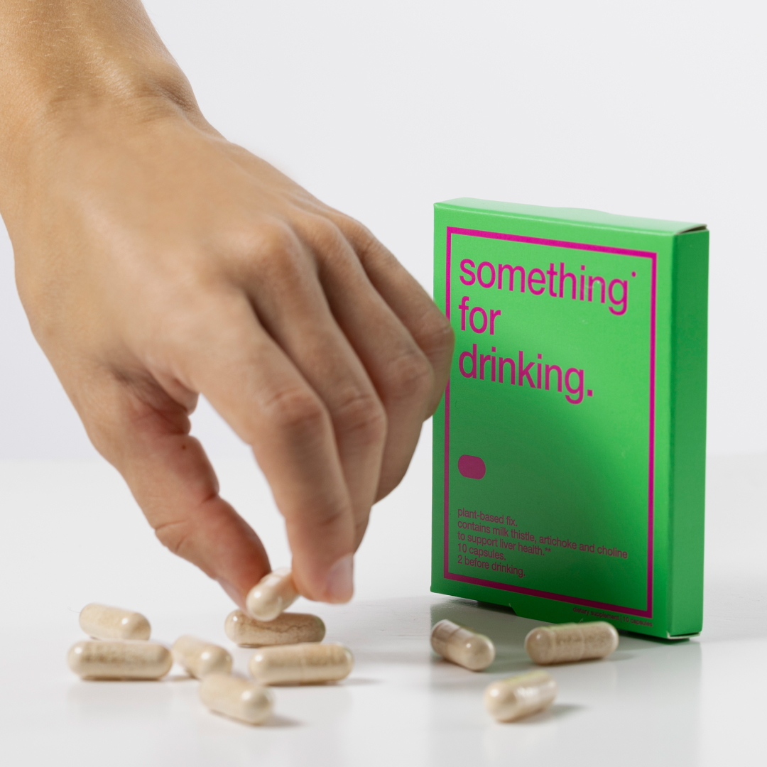 Hand reaching for capsules next to a green box labeled 'something for drinking.'