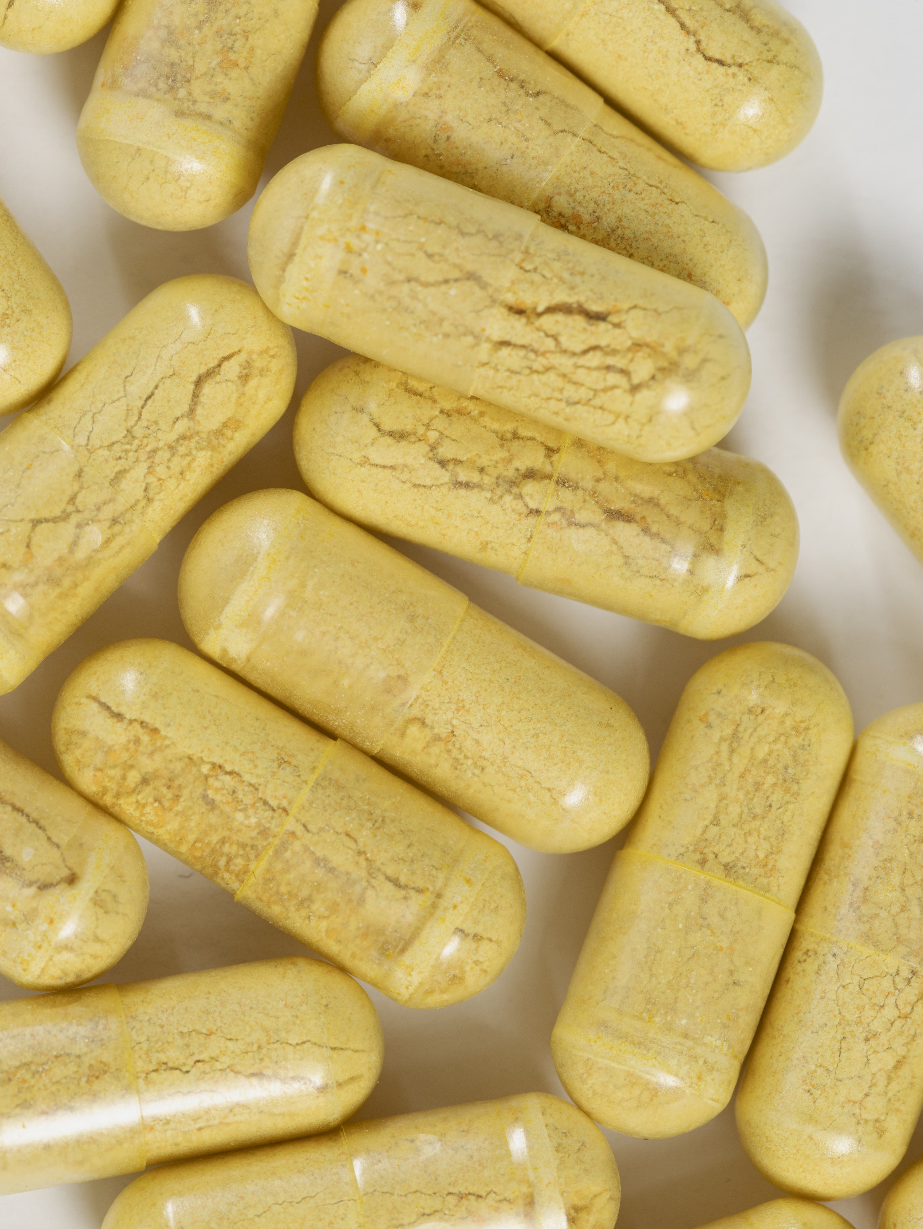 Close-up of yellow capsules with a textured surface on a white background.