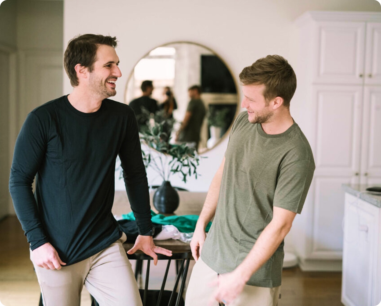 Two men smiling and talking in a modern kitchen.