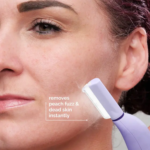 Close-up of a woman using a facial hair remover on her cheek.