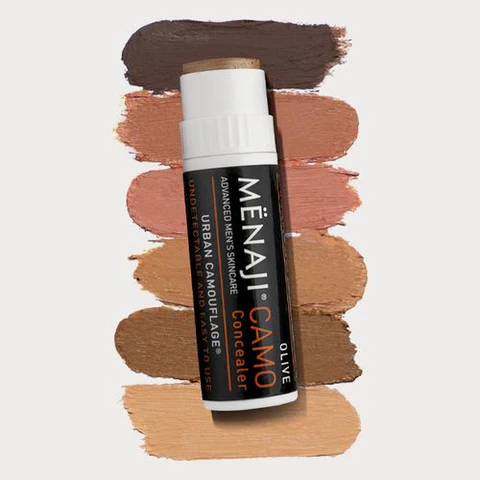A tube of MËNAJI CAMO Concealer on top of several swatches of different shades.