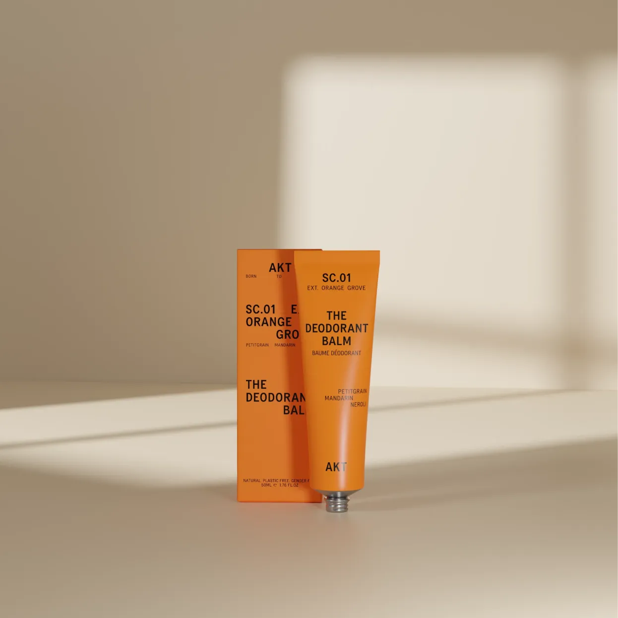 Orange deodorant balm tube with matching box on a beige surface.