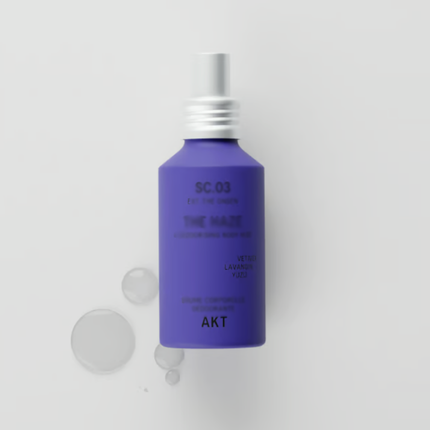 A matte purple bottle with a silver spray cap, labeled 'AKT SC.03', next to several clear liquid droplets.