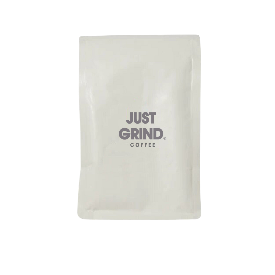 White coffee bag labeled 'Just Grind Coffee' with USDA Organic seal.