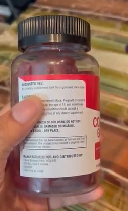 Hand holding a bottle with a red label and usage instructions on the back.