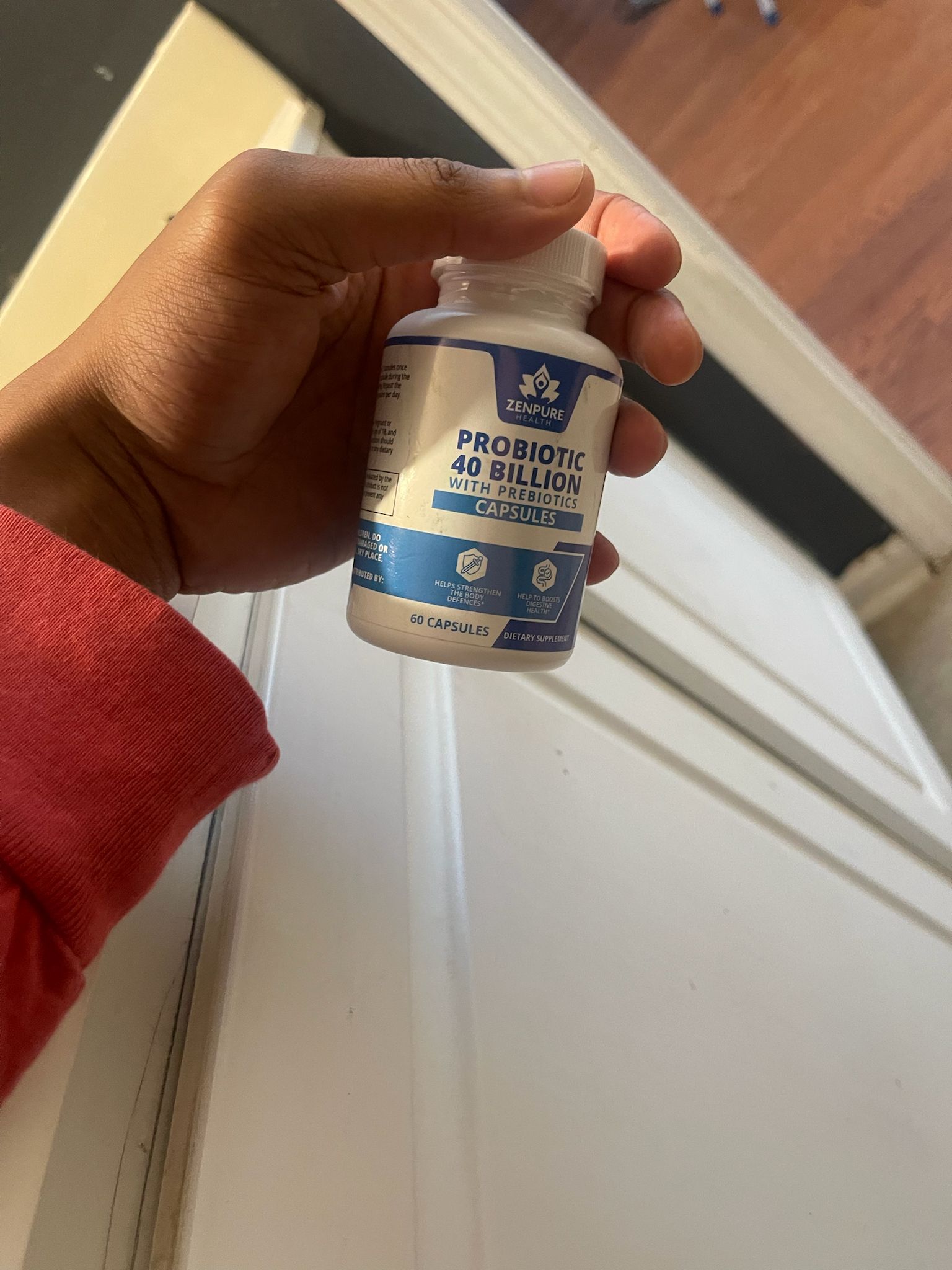 Hand holding a bottle of probiotic capsules.