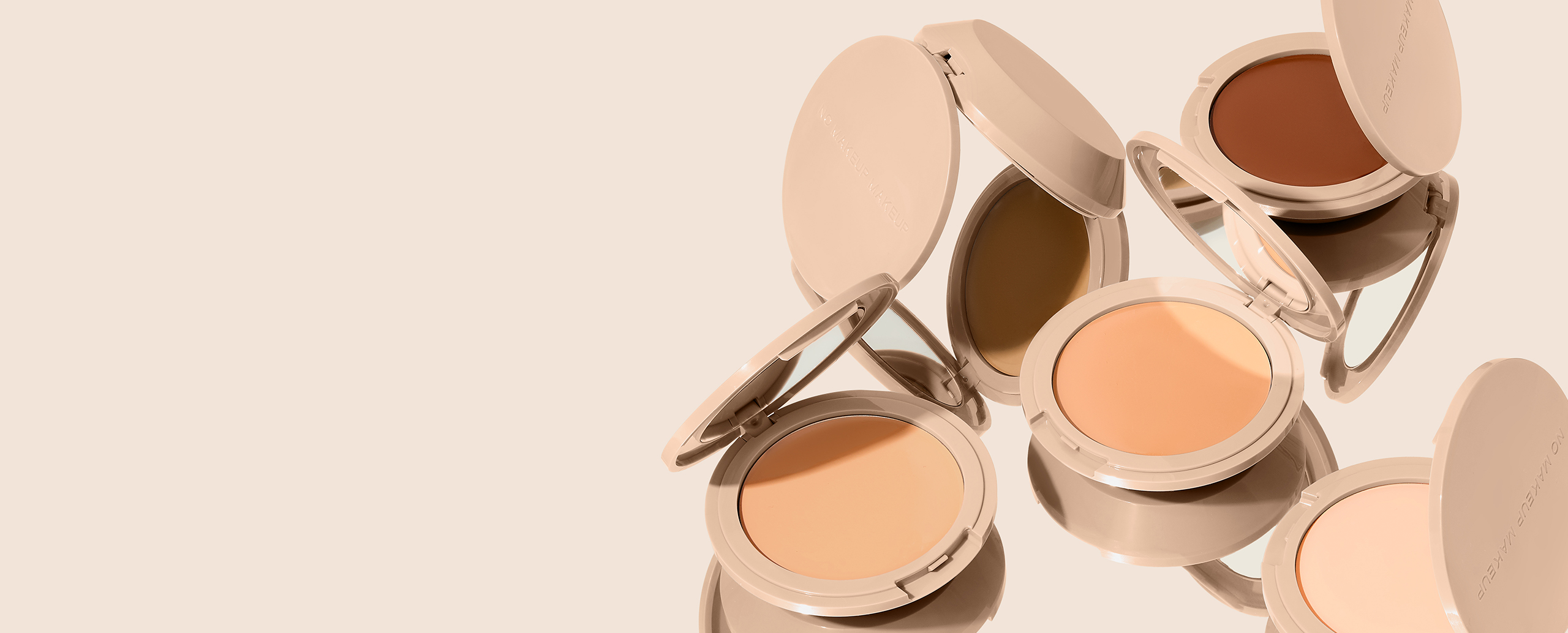 Three makeup compacts and brushes on a beige background.