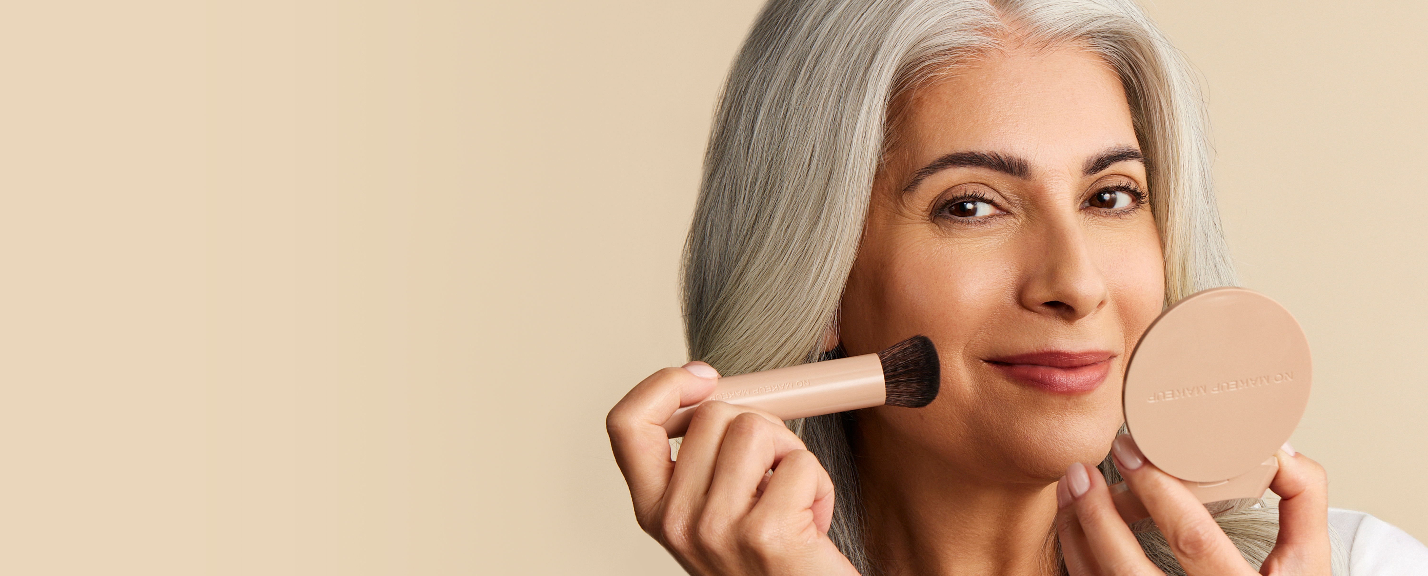 Three makeup compacts and brushes on a beige background.