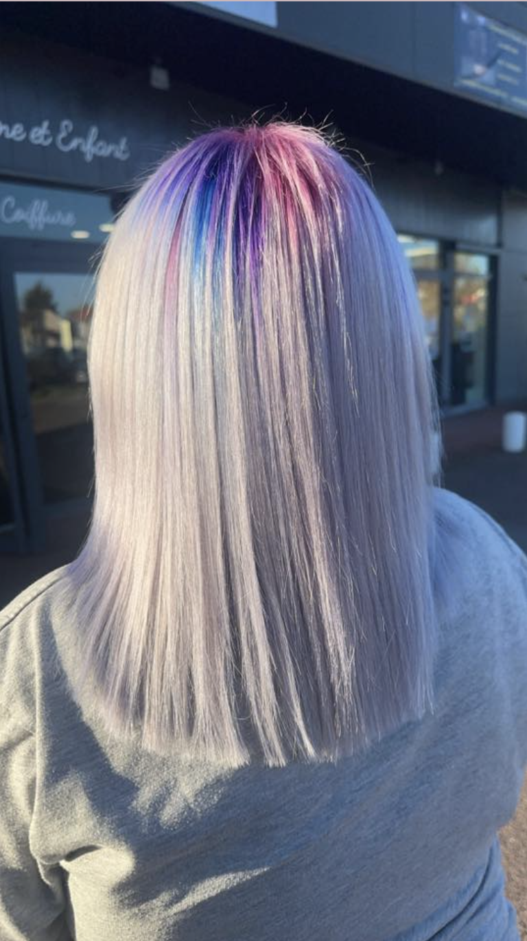 Back view of a person with straight, silver hair and vibrant purple, blue, and pink roots.