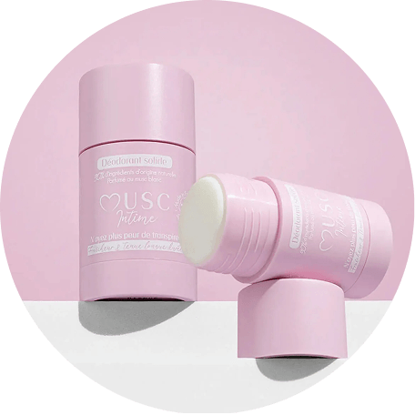 Two pink solid deodorant sticks, one open and one closed, on a pink and white surface.