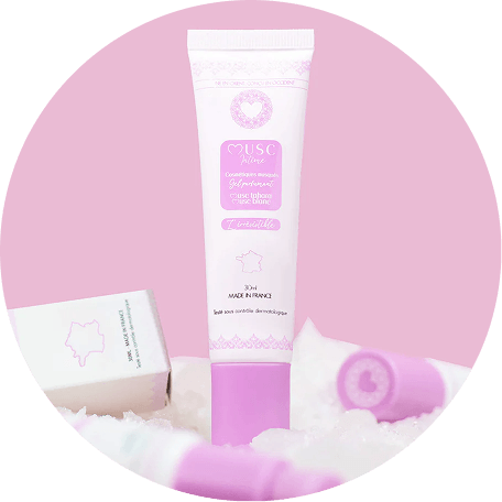 A tube of Musc Intime gel parfumé standing upright on a fluffy white surface against a pink background.