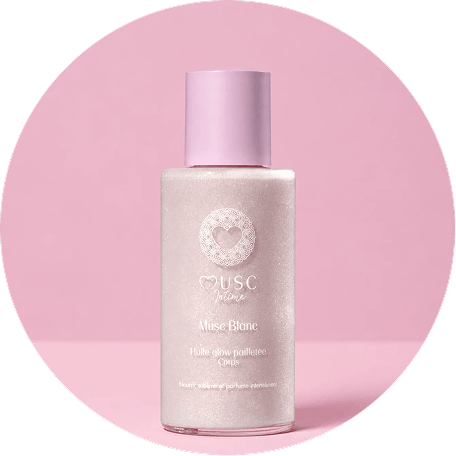 A bottle of shimmering white body oil with a pink cap, set against a circular pink background.