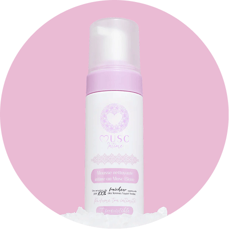 A white and pink bottle of Musc Intime foaming cleanser, set against a circular pink background.