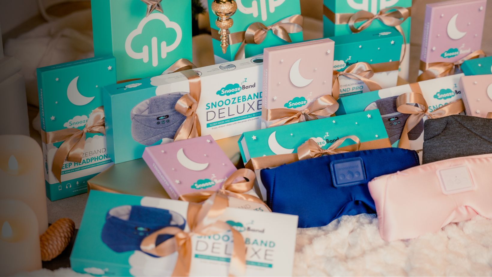 Gift-wrapped Snoozeband products with headphones and sleep masks displayed on a soft surface.