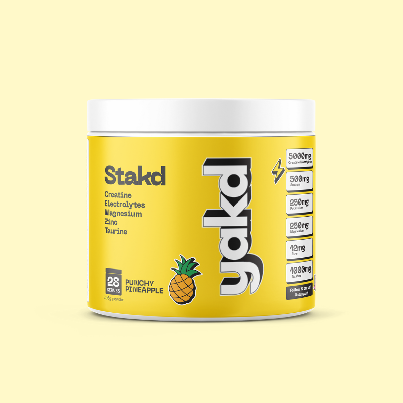 A white and yellow tub of Stakd Punchy Pineapple supplement powder against a pale yellow background.