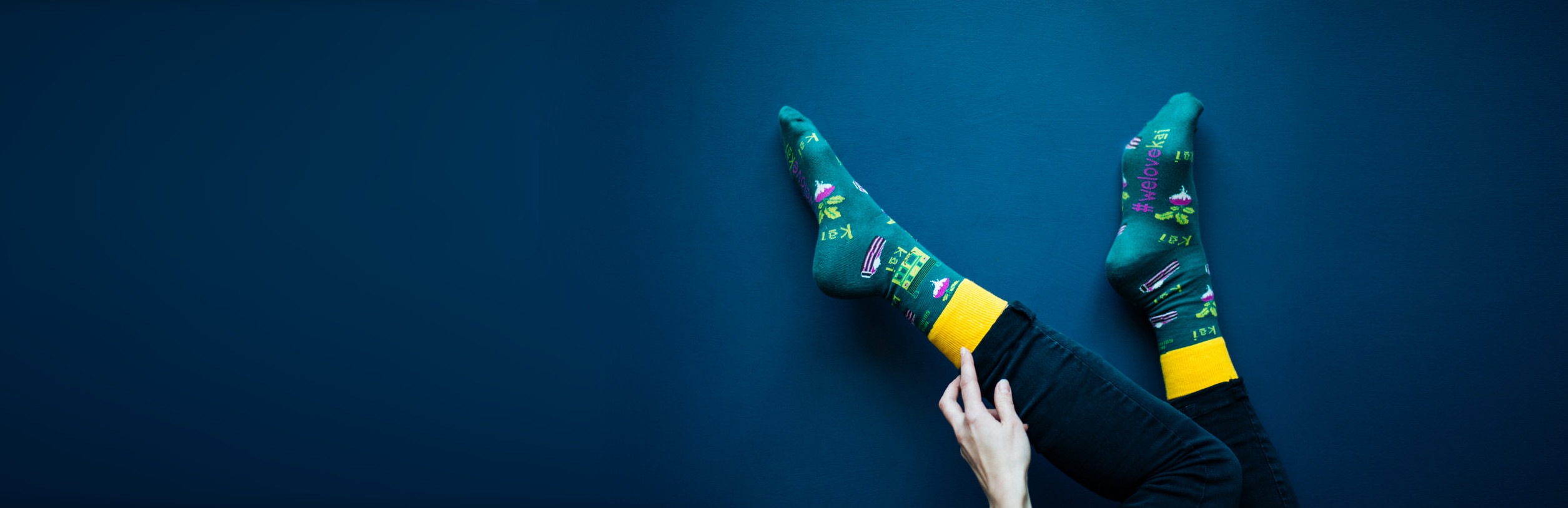 Person wearing colorful socks with patterns on a blue background.