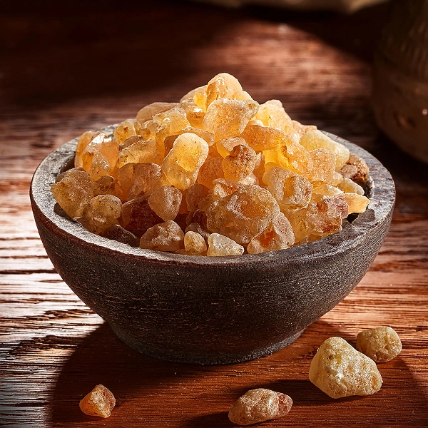 Bowl of amber-colored resin pieces on a wooden surface.