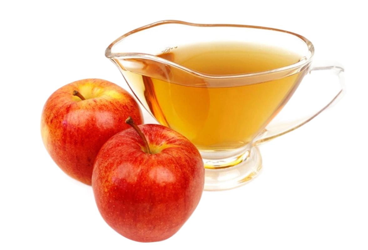 Two red apples next to a glass jug of apple juice.
