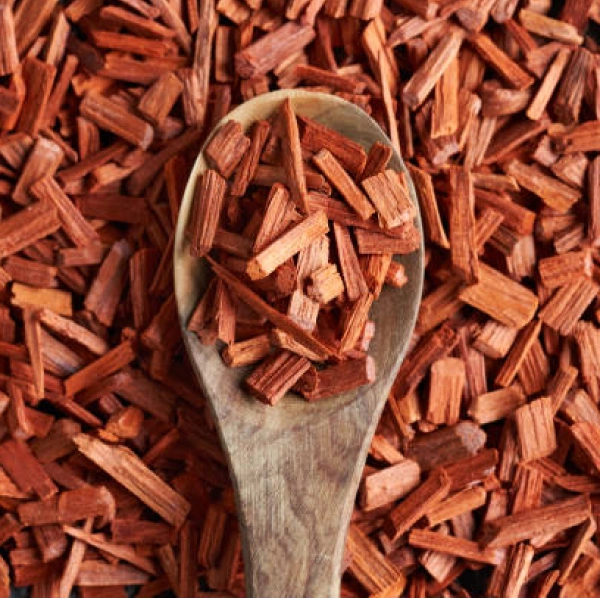 A wooden spoon filled with reddish wood chips.
