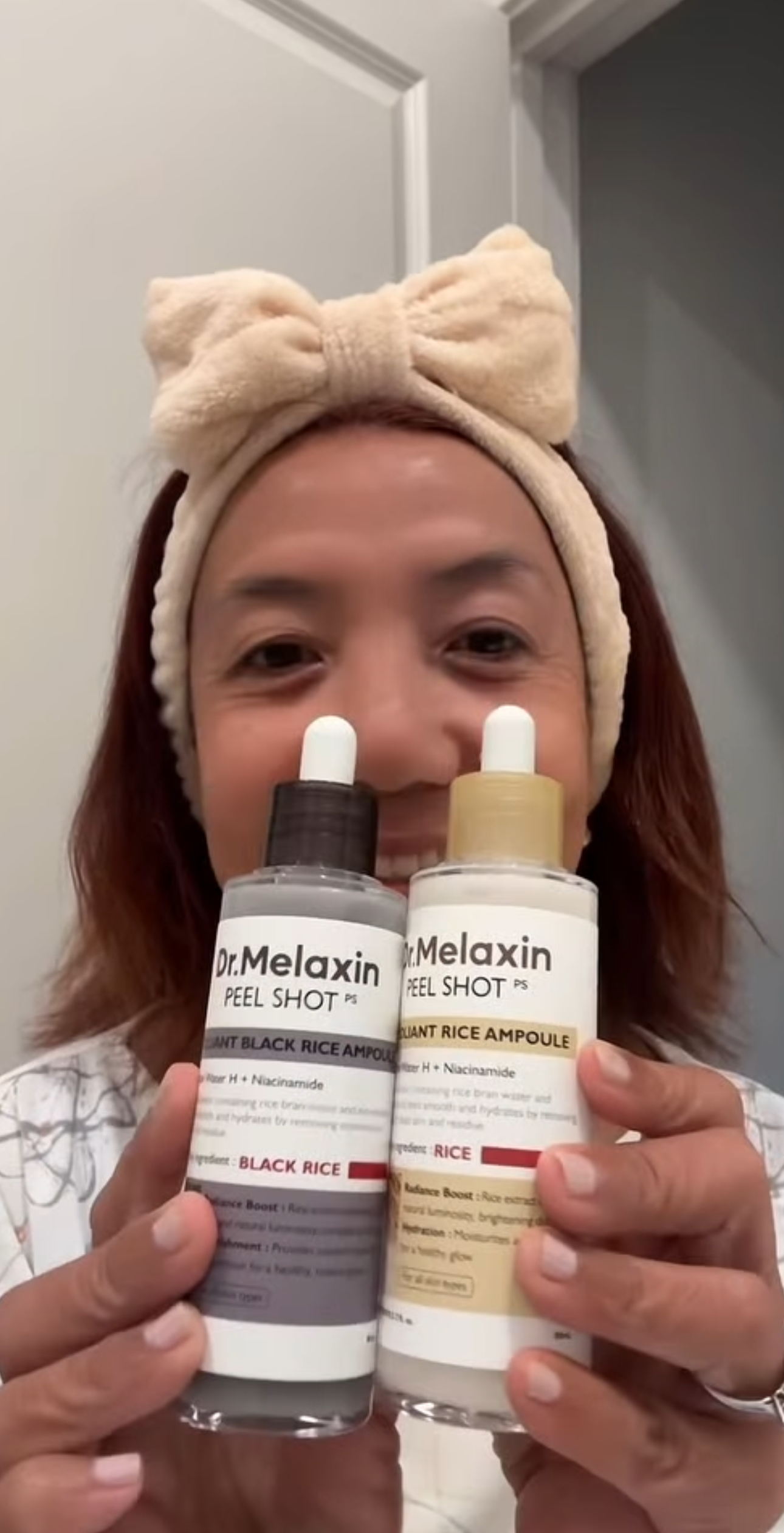 Person holding two skincare bottles labeled 'Dr. Melaxin Peel Shot' with a headband.