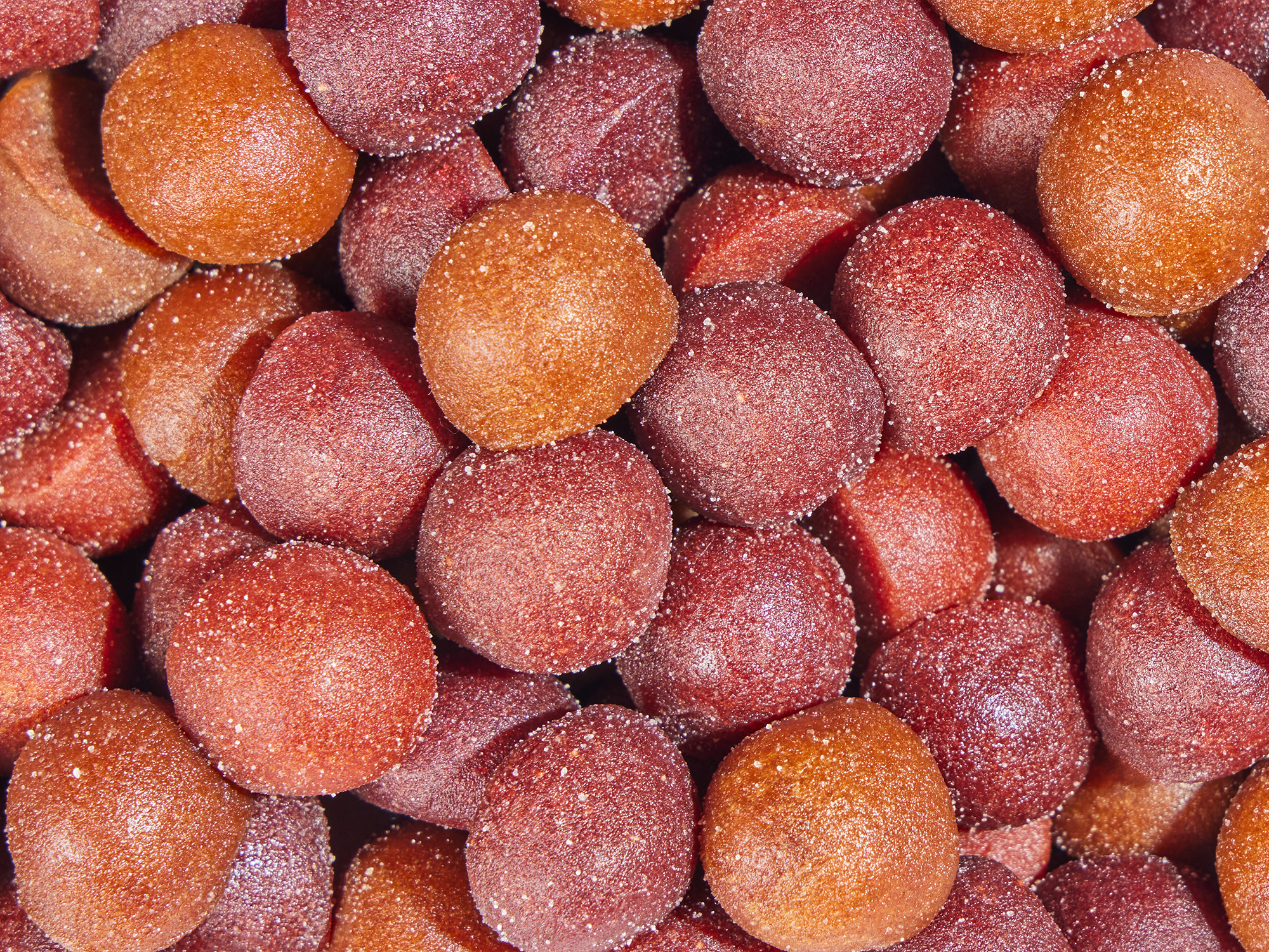 Close-up of sugar-coated, round, red and orange candies.