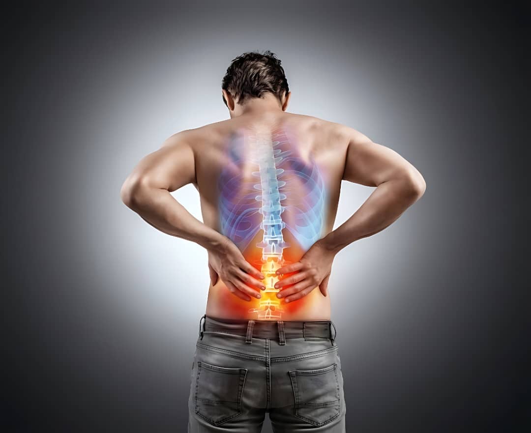 A man holds his lower back in pain, with an anatomical overlay of his spine highlighted in red.
