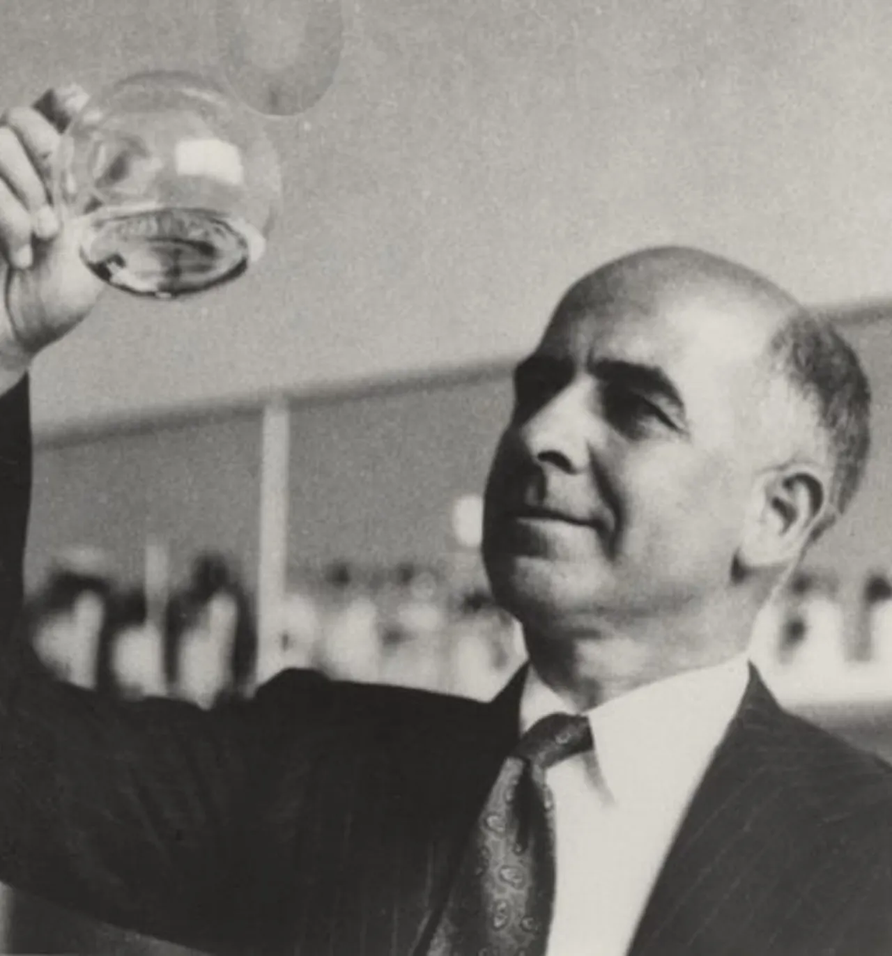 Man in suit holding a glass flask in laboratory.