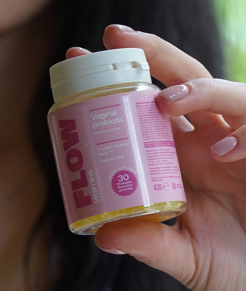Hand holding a bottle of vaginal probiotic gummies with pink label.
