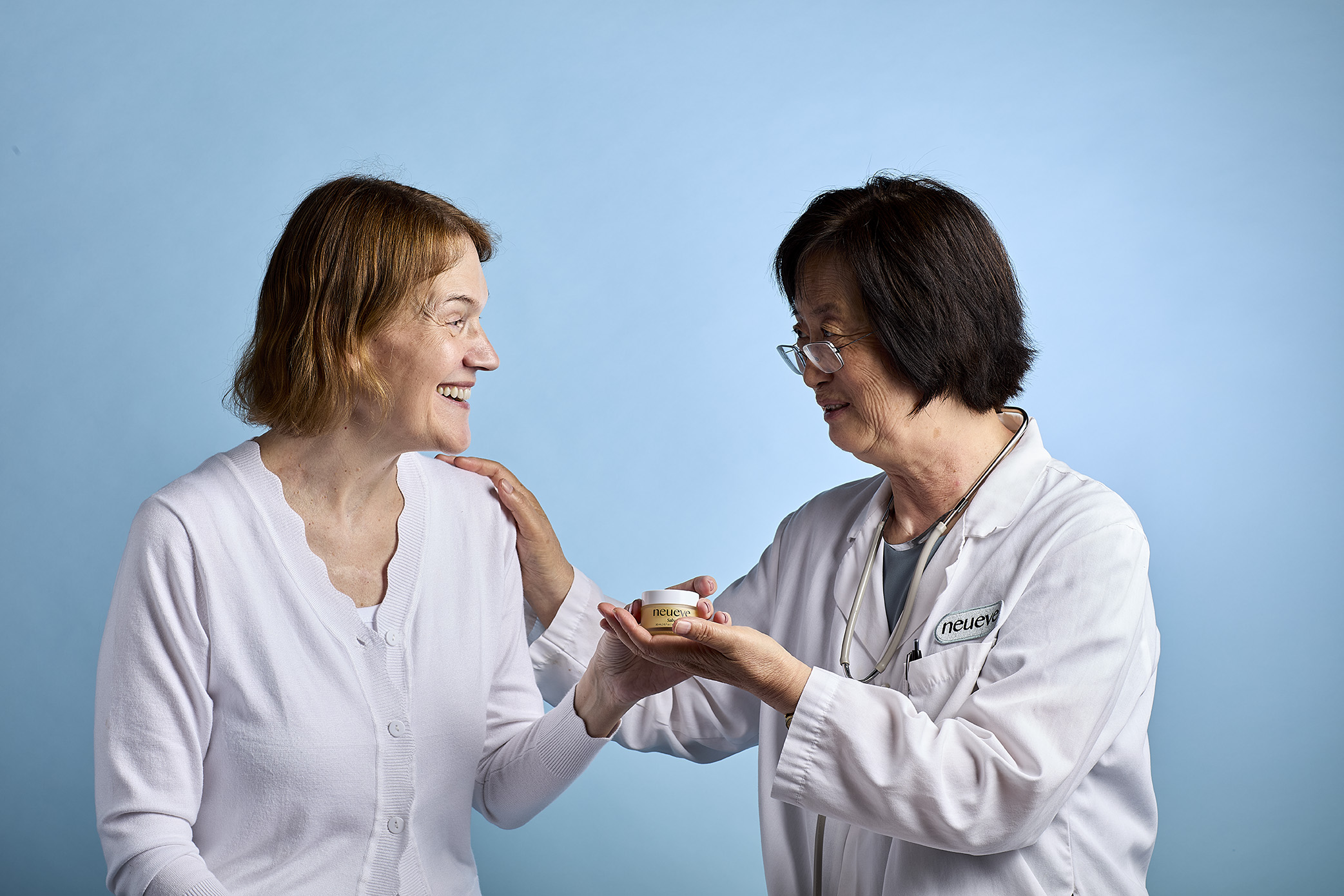 Smiling woman receives a small jar from a doctor in a white coat.