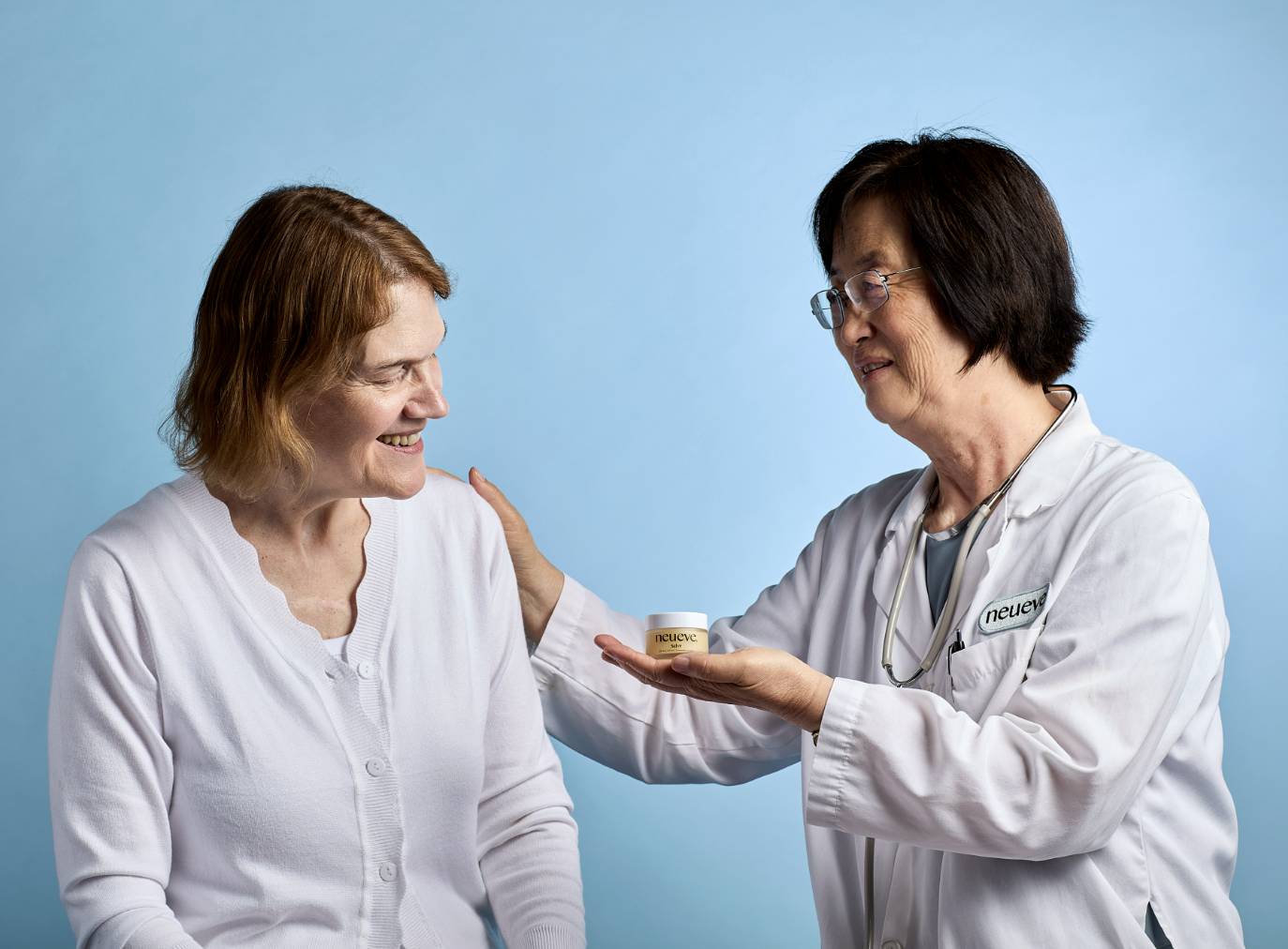 Two women, one in a lab coat, smiling and interacting with a product.
