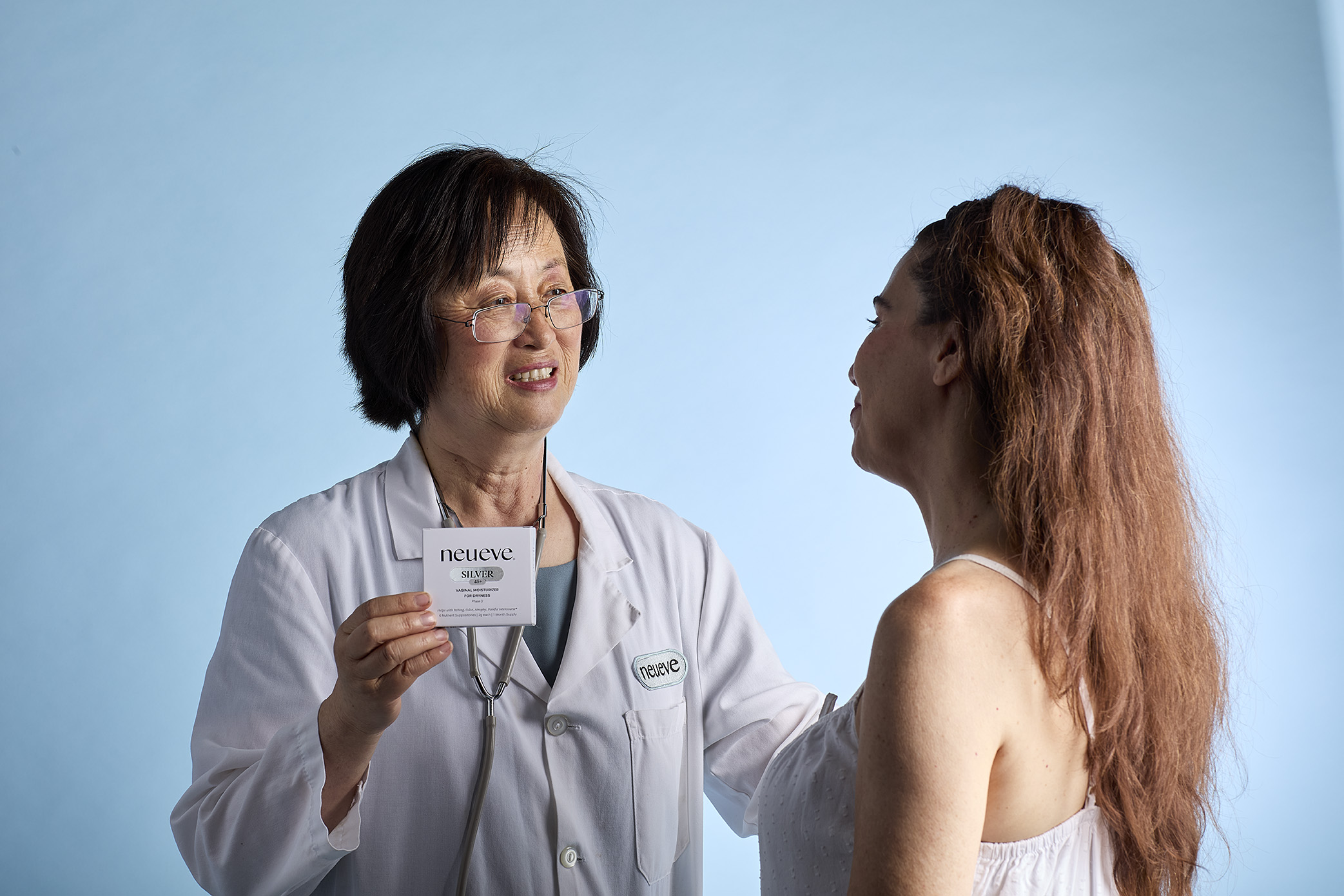 A doctor showing a product to a patient on a blue background.