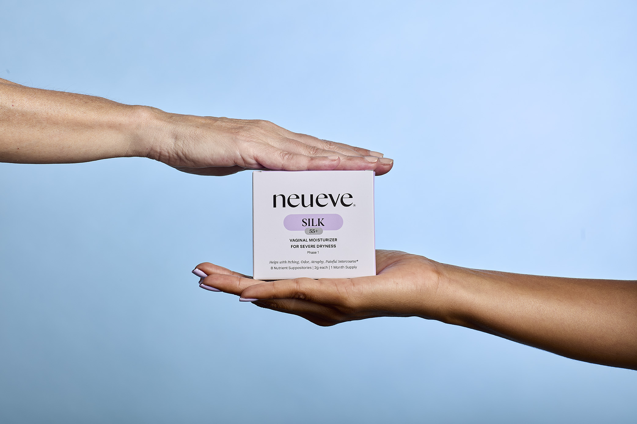 Two hands holding a box of NeuEve Silk on a blue background.