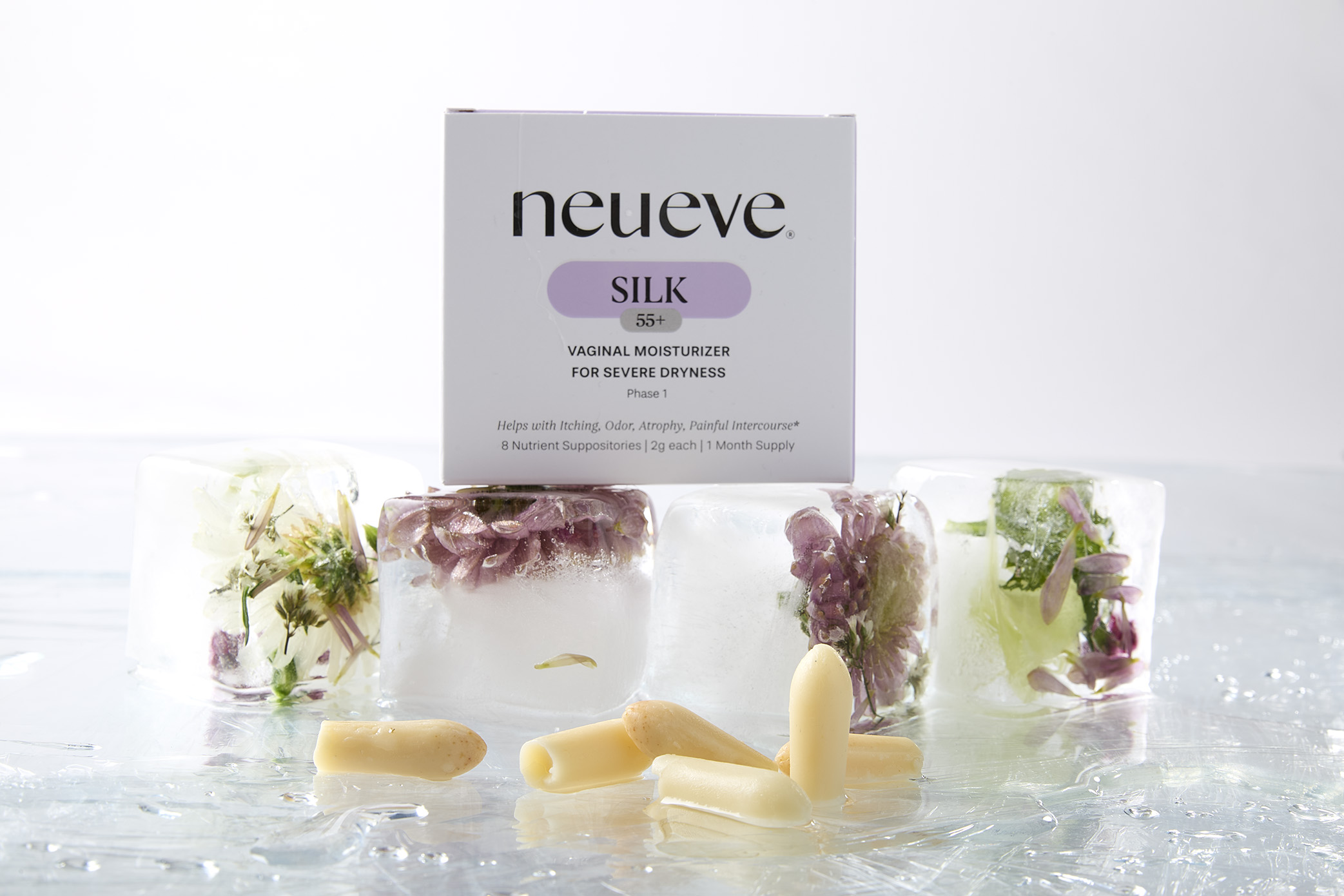 Product box with floral ice cubes and cream-colored capsules on a reflective surface.
