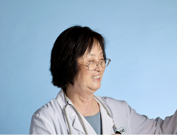 Smiling person in a white coat with a stethoscope against a blue background.