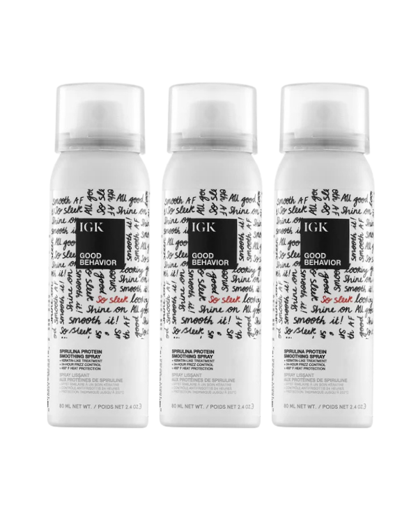 Three white spray bottles of IGK Good Behavior Spirulina Protein Smoothing Spray on a white background.